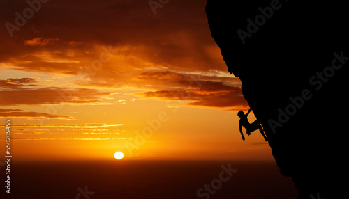 Climbing mountain, sunset silhouette and man sports exercise for fitness, rock training in nature and workout during travel in Canada. Athlete with freedom against orange sunset sky background © David L/peopleimages.com