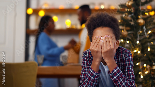 Sad, desperate little boy closing eyes during parents quarrel on christmas eve