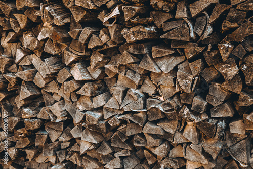 Chopped firewood pile. Woodpile wall. Heap of old dry pine woods. Brown textured background. Natural solid fuel resources. Winter preparation. Countryside pattern. Rustic style details. Woodworking