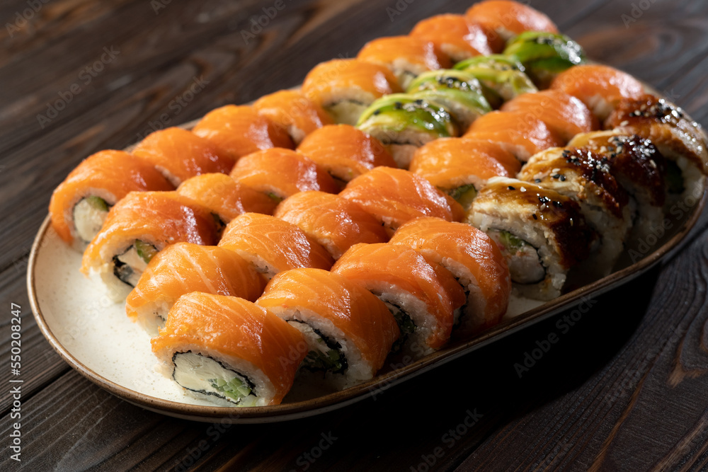 Sushi roll set Philadelphia with salmon, avocado, cream cheese on wooden background. Sushi menu. Japanese food Sushi roll set Philadelphia with salmon, avocado, cream cheese on wooden background. Sushi menu. Japanese food