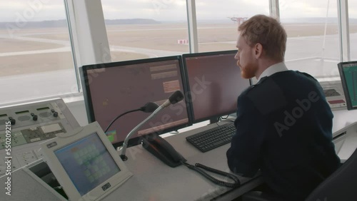  Surveillance Officer looking at Computer Screen in Central Office for air traffic control. Realtime photo