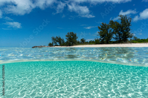 Fototapeta Naklejka Na Ścianę i Meble -  Split Shot of deserted island in the bahamas. Clear blue aqua water with sun rays shining through to white sandy bottom. 