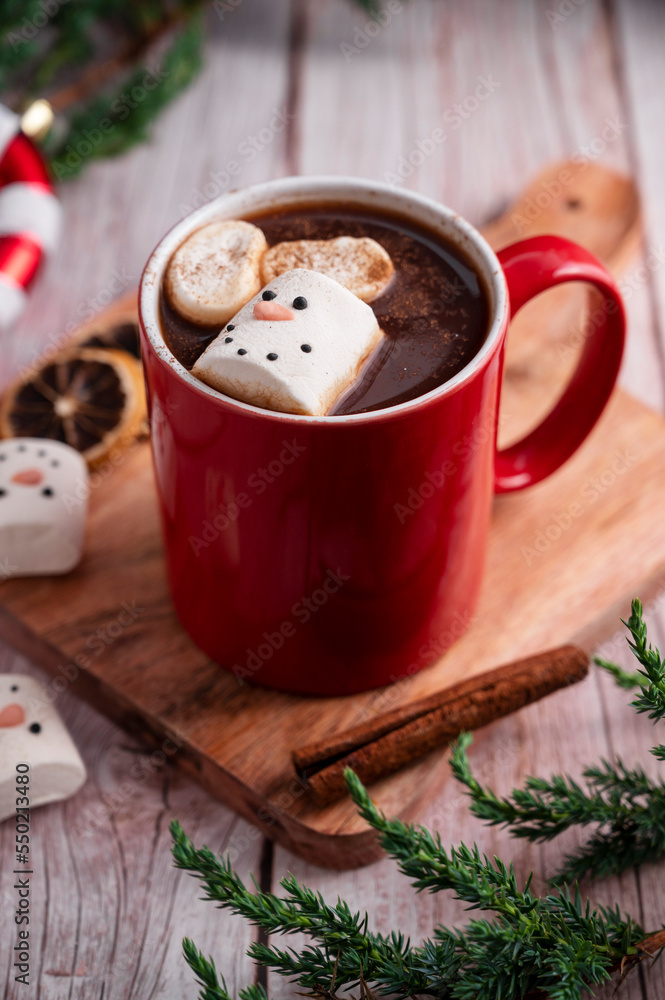 Red mug with hot chocolate and melted marshmallow snowman, rustic wooden festive background