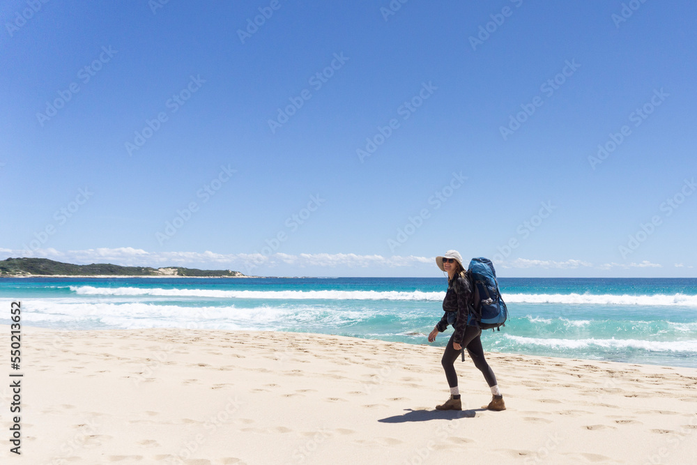 Hiker hiking with backpack along beach on cape to cape track in western australia