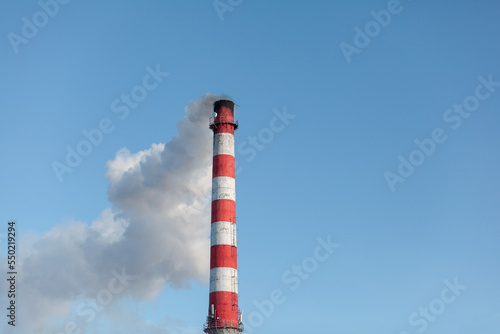 White thick smoke from the boiler room chimney. Smoke against the blue sky. Air pollution. Heating of the city. Industrial zone.