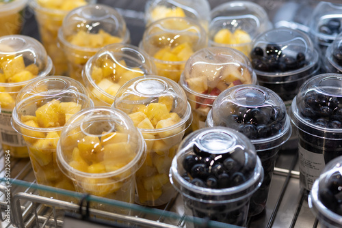 Close up of plastic cups filled with chopped fruits and berries. Eco-friendly  organic and healthy snack. Food on shelf in supermarket