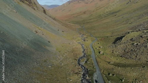 Aerial Drone Shot Panning Up Revealing Honister Pass Road Mountain Pass on Sunny Day with Clouds Lake District Cumbria United Kingdom photo