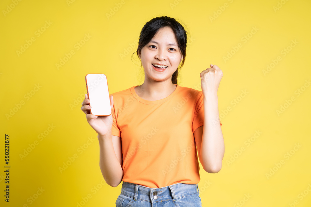 image of asian girl holding phone and isolated on yellow background