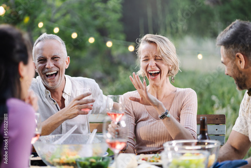 Sticker Couple having fun time at dinner with friends, laughing and drinking wine