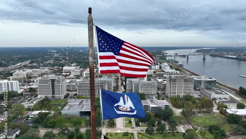 USA and Louisiana state flag wave in breeze. Aerial from atop state capitol building. View of downtown Baton Rouge and Mississippi River. photo