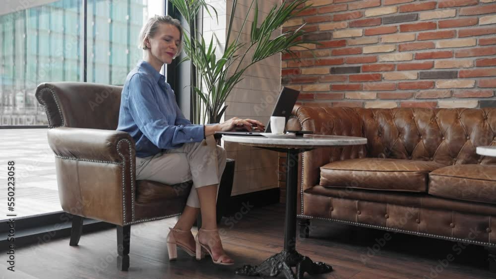 Stylish woman entrepreneur using laptop sitting in cafe. Inspired business female having a coffee while working Stylish woman entrepreneur using laptop sitting in cafe. Inspired business female having a coffee while working