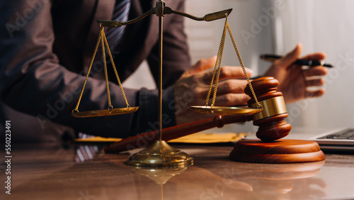 Justice and law concept.Male judge in a courtroom with the gavel, working with, computer and docking keyboard, eyeglasses, on table in morning light