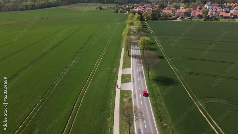 aerial view of road passing through green field agricultural land with cyclist and car traffic pollution aerial view of road passing through green field agricultural land with cyclist and car traffic pollution