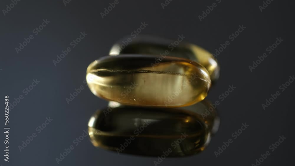 Omega 3 Gold oil capsules on black background, rotation. Close-up of rotating golden pills.Vitamins supplements pills omega 3. Cod liver oil medicines. Fish oil capsules.Omega 3 Fish oil vitamin gel Omega 3 Gold oil capsules on black background, rotation. Close-up of rotating golden pills.Vitamins supplements pills omega 3. Cod liver oil medicines. Fish oil capsules.Omega 3 Fish oil vitamin gel