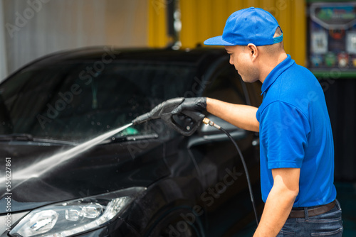 Man worker washing car service. Car wash cleaning station high pressure water. Employees clean a vehicle professionally. © Chanakon