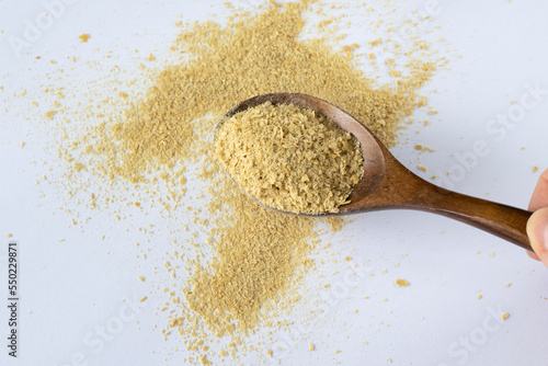 Non-enriched dry food yeast in a wooden spoon on a white background. Healthy nutrition, a supplement to food.