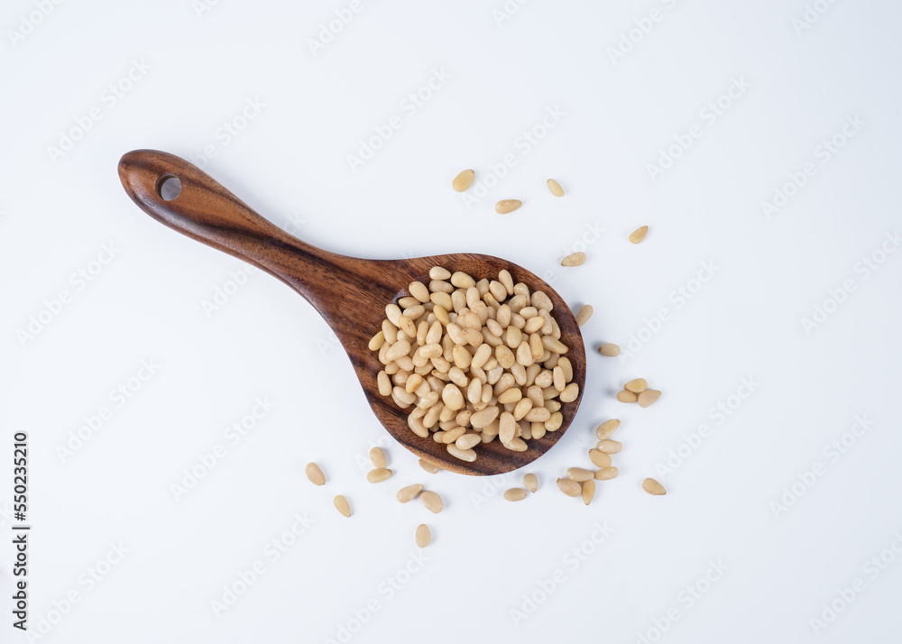 raw pine nuts with a japanese rice spoon on a white background raw pine nuts with a japanese rice spoon on a white background