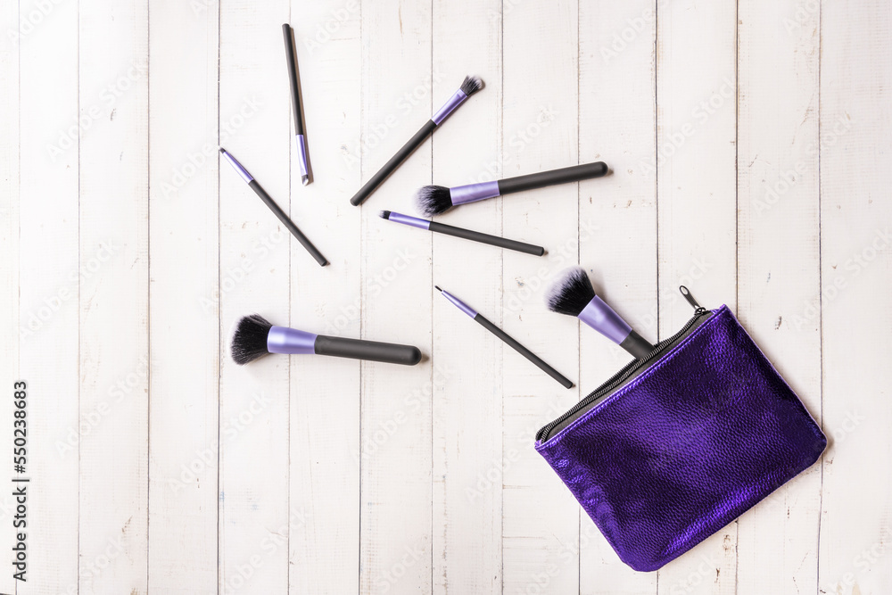 A purple bag with brushes of different sizes scattered on the white table