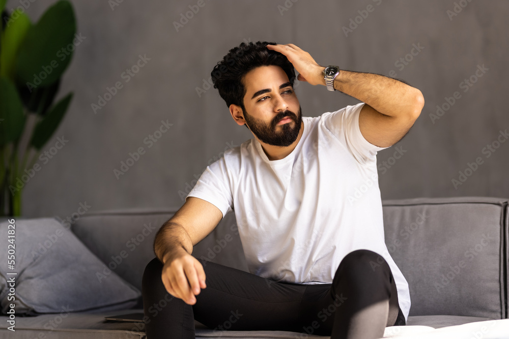 Serene relaxed barefoot young african man resting on comfortable couch in modern living room holding hands behind head Serene relaxed barefoot young african man resting on comfortable couch in modern living room holding hands behind head