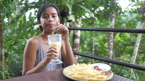 A Skinny young Asian woman eating fries and drinking sweet cold fruitshake photo