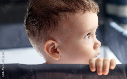 adorable baby boy sitting in toddler infant crib looking on side or forward biting bed edge.maternity motherhood concept sitting home with child day time sleep concept big beaituful eyes naked photo