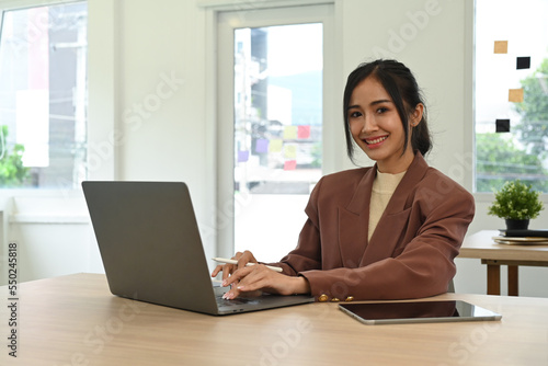 Beautiful asian female investor working online, analyzing financial online data on laptop computer