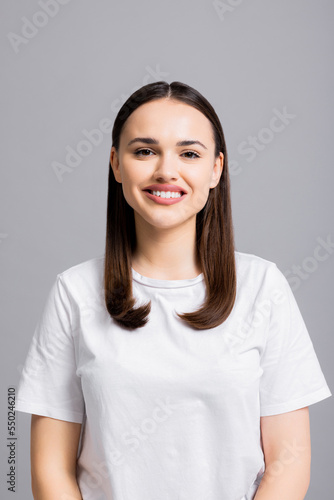 Portrait close up shot of beautiful adorable pretty woman looking at camera smiling with white teeth standing on grey background isolated.