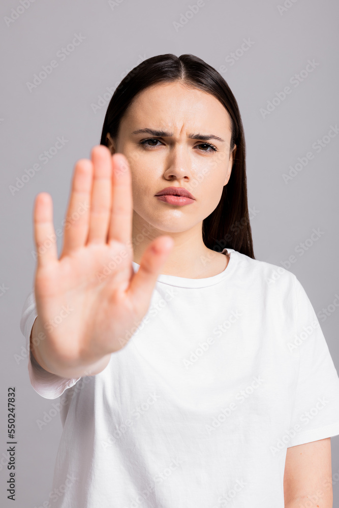 Serious concentrated young woman wearing white t-shirt looking at camera saying stop to domestic violence and abuse protesting againsta abortion discrimination nonverbal language. Serious concentrated young woman wearing white t-shirt looking at camera saying stop to domestic violence and abuse protesting againsta abortion discrimination nonverbal language.