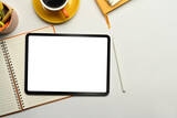 Flat lay digital tablet with blank screen, cup of coffee and blank notepad on white table. Top view with copy space