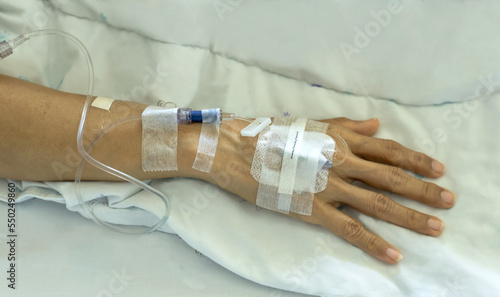 Close up patient with saline tube and intravenous catheter for injection plug in hand at hospital