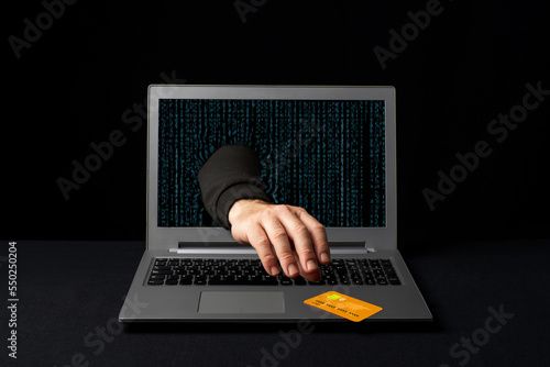 A cybercriminal reaching through a laptop to steal an online shopper's credit card. Internet scams