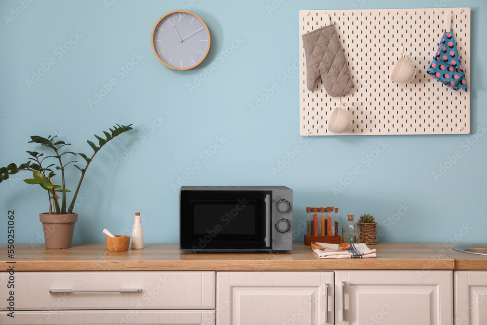 Interior of stylish kitchen with microwave oven near light blue wall Interior of stylish kitchen with microwave oven near light blue wall