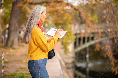 Inspired woman with an albom in hands on the river bank photo