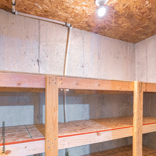 Square Unfinished small storage room with concrete walls and wooden shelves