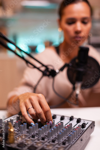 Influencer in entertainment industry smiling and checking sound during broadcast from home studio in the night. Recording digital social media communication