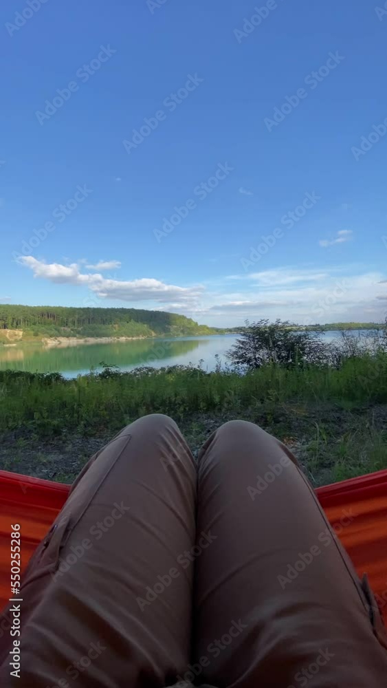 first person view sitting on hammock looking at lake first person view sitting on hammock looking at lake
