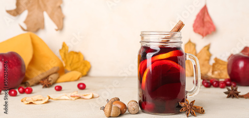 Mason jar of tasty mulled wine and autumn leaves on light table