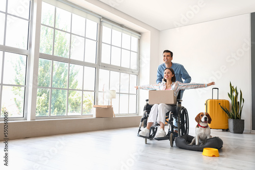 Happy young man with his wife and dog in wheelchair in their new flat on moving day