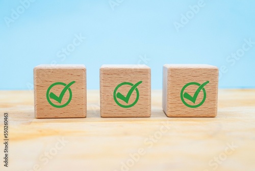 Checklist, Corporate regulatory and compliance, approve, Quality control management, ISO certification, service quality warranty concept. Check mark icon on wooden cube blocks on blue background with  photo