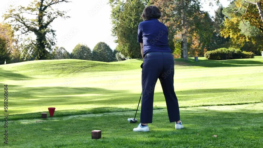 Golfer Teeing Off with Her Driver on Golf Course in a Sunny Day in Autumn in Lugano, Ticino, Switzerland. Golfer Teeing Off with Her Driver on Golf Course in a Sunny Day in Autumn in Lugano, Ticino, Switzerland.