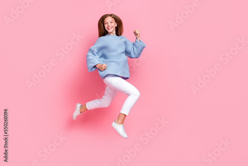 Full body photo of young beautiful funky energetic school girl teenager jumping air trampoline fists up celebrate isolated on pink color background