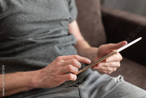 Man sitting on a couch with a tablet in his hands. Using technology.