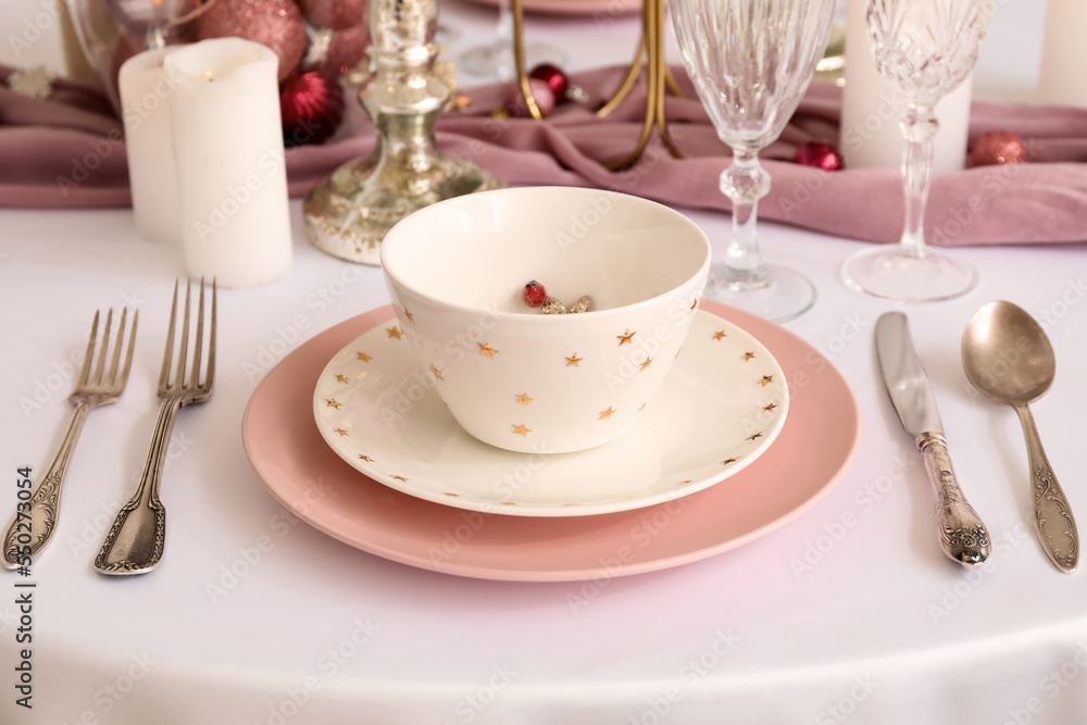 Christmas table setting with pink and white plates in dining room, closeup