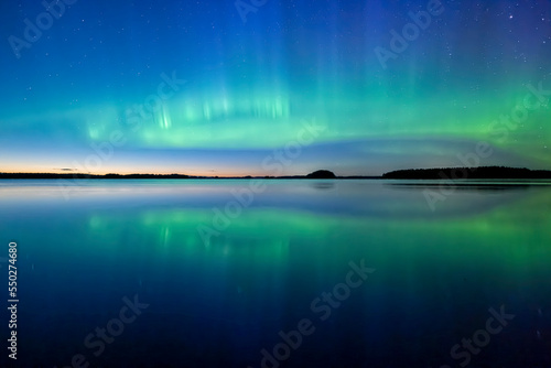 Northern lights dancing over lake in Farnebofjarden national park in north of Sweden.