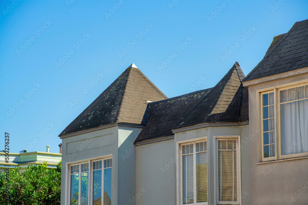 Beige stucco apartment building with multiple unit as a detail shot with copy space clear blue sky and brown castle style roofs Beige stucco apartment building with multiple unit as a detail shot with copy space clear blue sky and brown castle style roofs