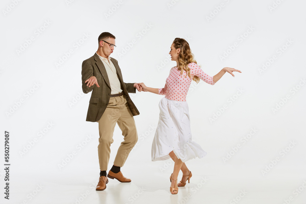 Naklejka premium Young excited man and woman in 60s american fashion style clothes dancing retro dance isolated on white background. Music, energy, happiness, mood, action