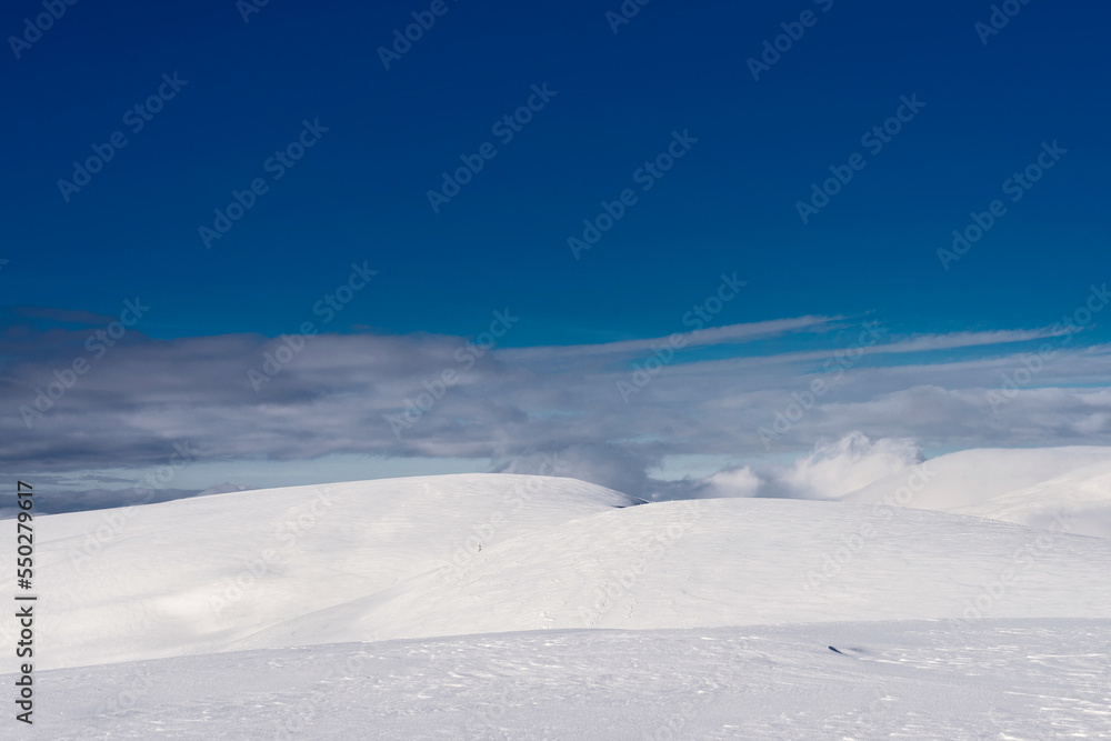 Snow-covered mountain range. Clouds over the mountain ridge. Winter mountain landscape.