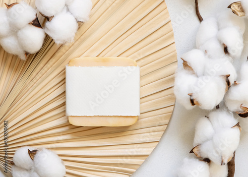 Soap bar with blank label on dried palm leaf with cotton flowers top view, wedding mockup