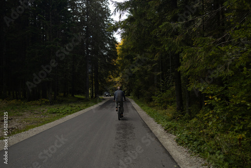 Male athlete mountain biker rides a bike on a forest path. Mysterious view. Autumn hike in the forest. Adventures in nature. Active lifestyle