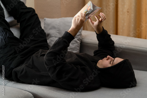 Young person reading a book relaxing on the sofa at home.